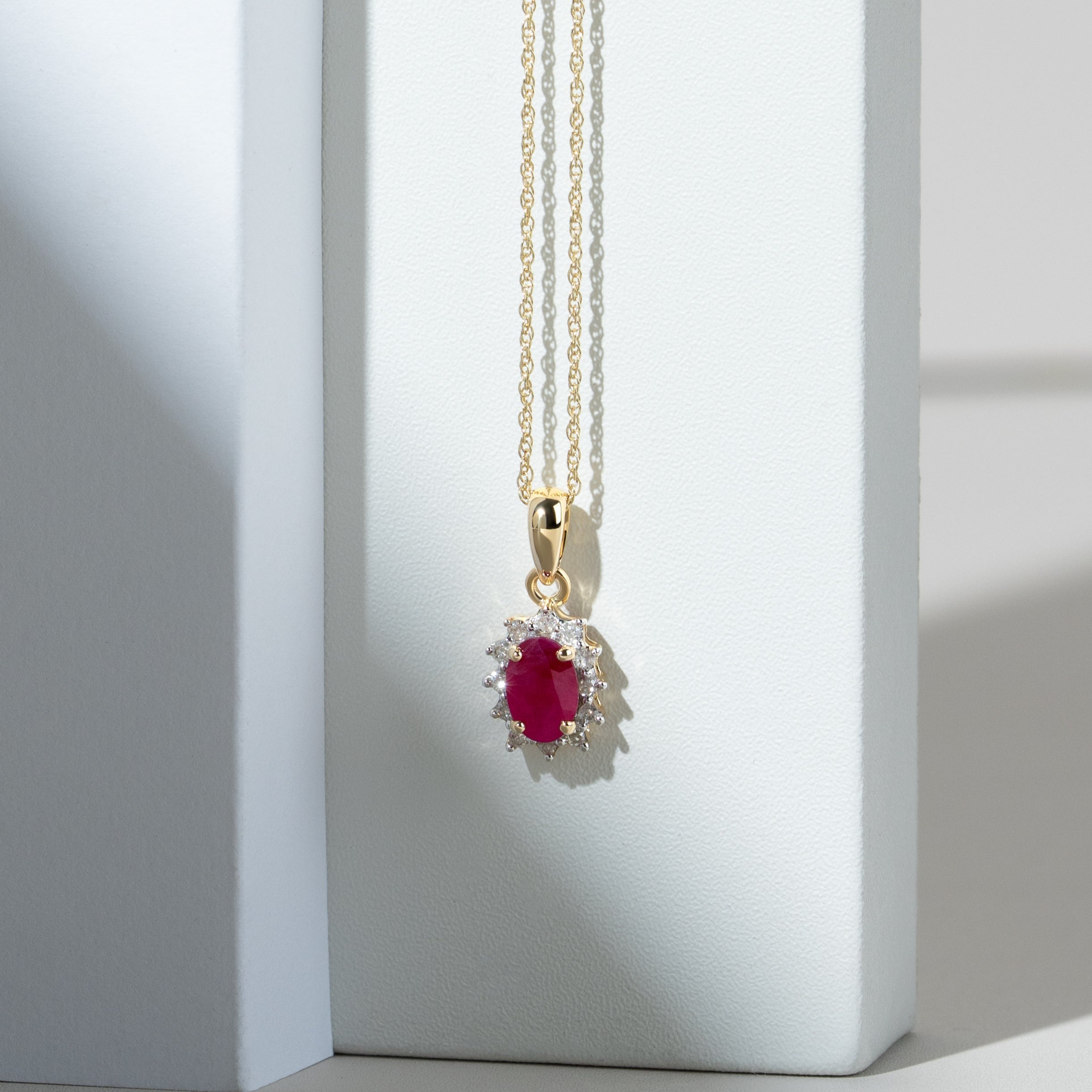 Colgante clásico en racimo ovalado de rubíes y diamantes en oro amarillo de 9 quilates