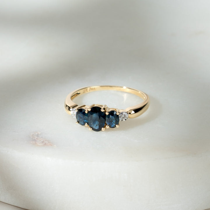 Anillo trilogía clásico de diamantes y zafiros ovalados en oro amarillo de 9 quilates