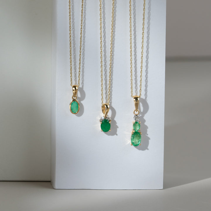Colgante clásico de dos esmeraldas ovaladas y diamantes en oro amarillo de 9 quilates
