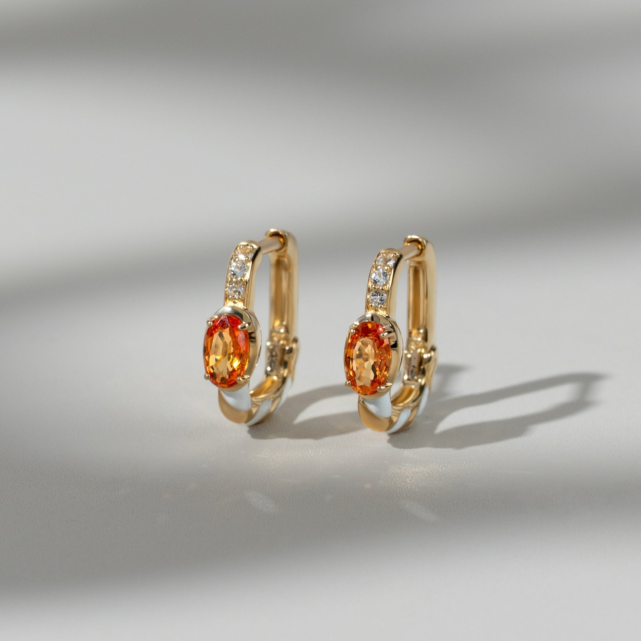 Aretes tipo argolla con topacio siberiano y zafiro naranja en oro de 9 quilates