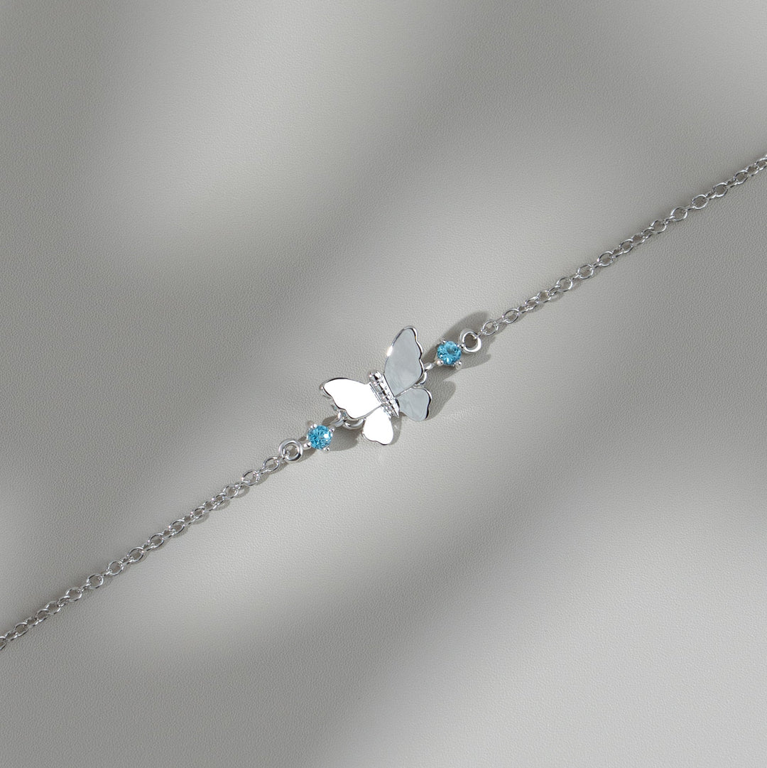 Brazalete clásico de mariposa con topacios azules redondos en oro blanco de 9 quilates